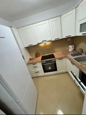 Modern kitchen with white units and wooden countertops.