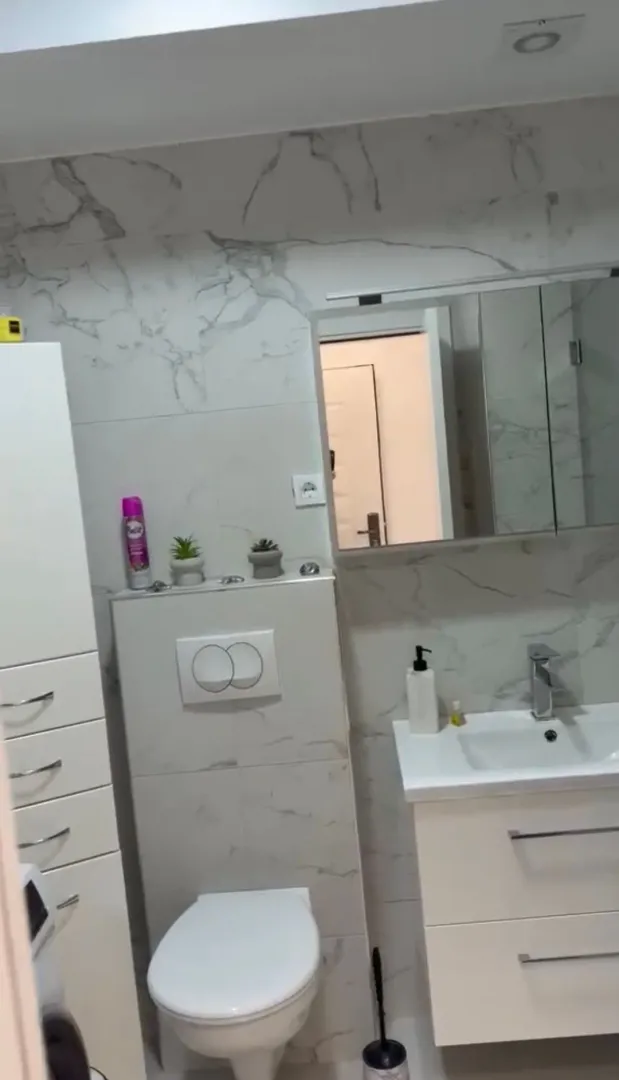Modern bathroom with a sink, toilet, and marble-look tiles.