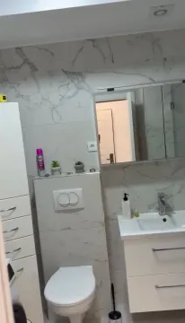 Modern bathroom with a sink, toilet, and marble-look tiles. - image 5