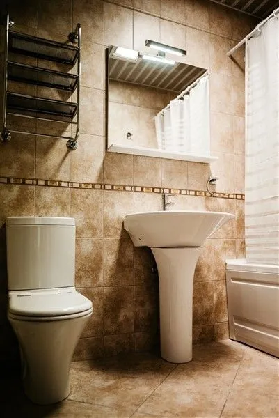A bathroom with beige tiles, a sink, and a mirror.