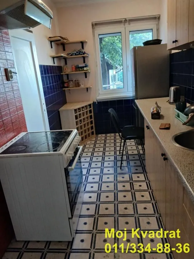 Small kitchen with a stove, refrigerator, sink, and open shelves.
