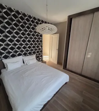 Bedroom with a large double bed, wardrobe, and decorative wallpaper. - image 6