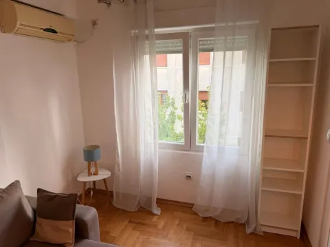 Living room with a sofa, bookshelf, and air conditioning unit. - image 4