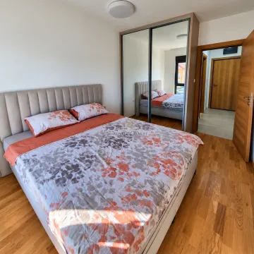 Prostrana spavaća soba sa bračnim krevetom, velikim garderoberom sa ogledalom i drvenim podom. - image 6