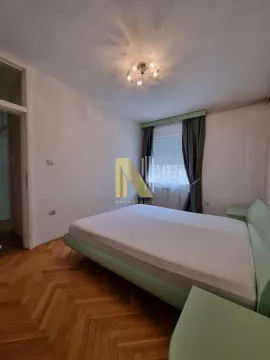 Nameštena spavaća soba sa bračnim krevetom i parketom na podu. - image 6