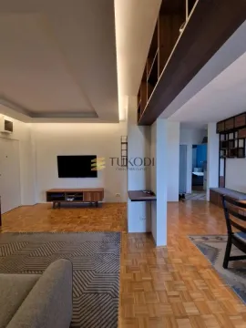 Living room with wooden flooring, a wall-mounted TV, and a dining area. - image 5