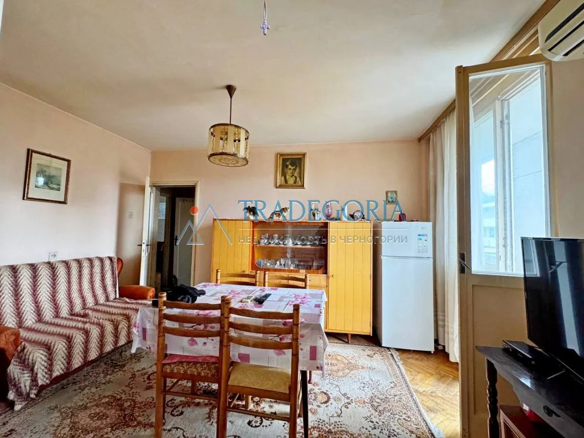 Dnevni boravak sa garniturom za sjedenje, trpezarijskim stolom i namještajem.