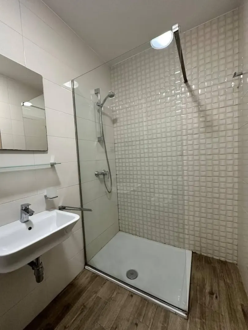 Moderno opremljeno kupatilo sa tuš kabinom i umivaonikom.