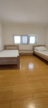 Bedroom with two single beds and wooden flooring. - image 5