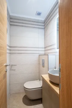 Small bathroom with a toilet, washbasin, and tiles in neutral tones. - image 11