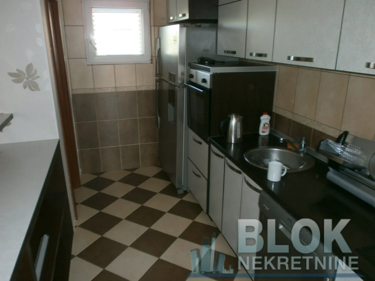 Smaller kitchen with white and dark cabinets and a refrigerator.