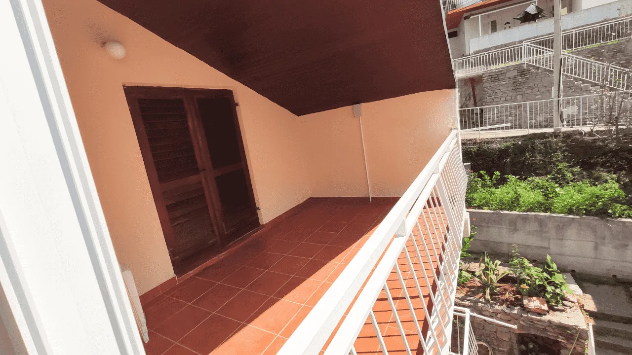 Natkriveni balkon sa popločanim podom i pogledom na dvorište.