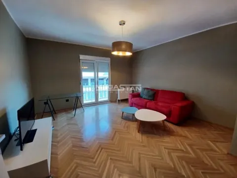 Dnevna soba sa crvenim kaučem, stočićima, televizorom i izlazom na terasu. - image 2