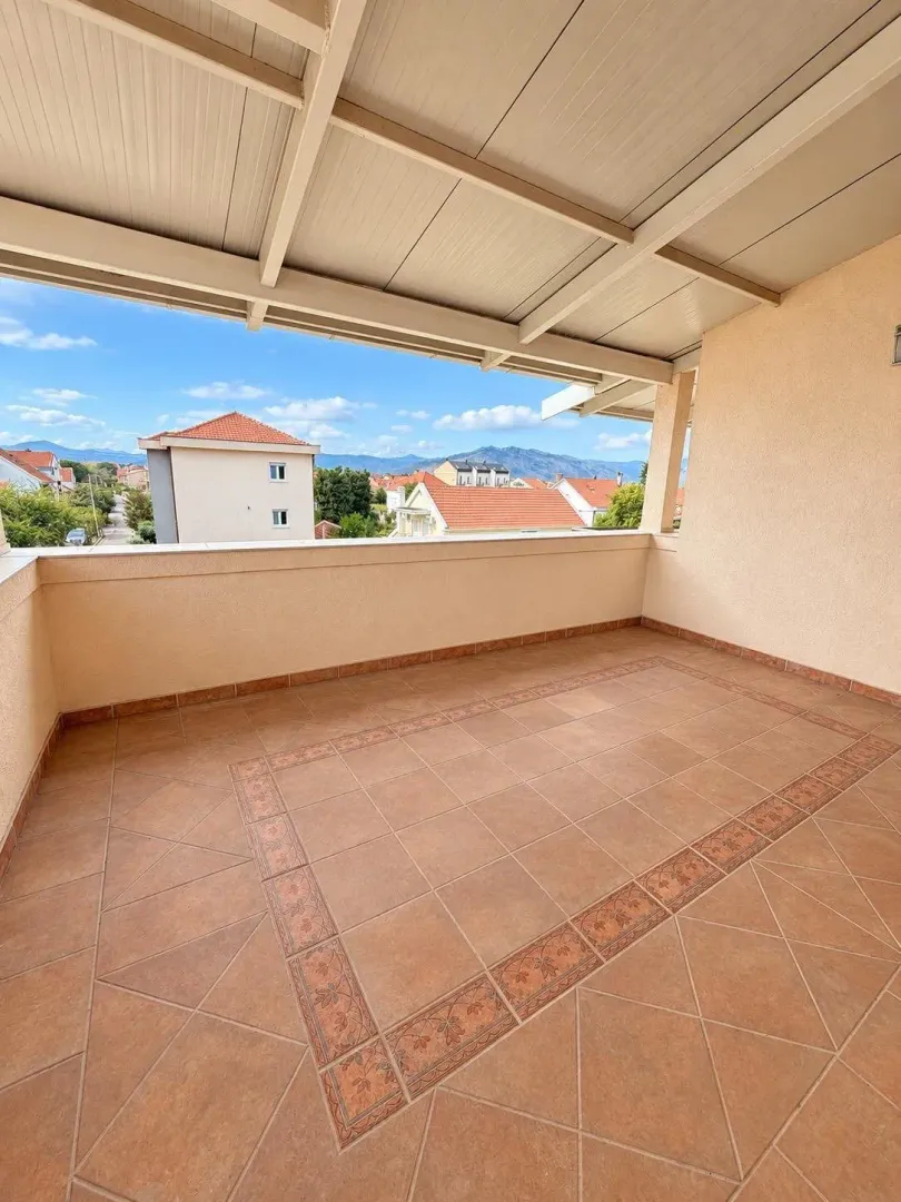 Spacious covered terrace with ceramic tiles and a view of the surroundings.