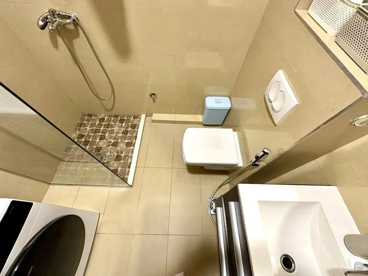 Pogled odozgo na kupatilo sa tuš kabinom, WC šoljom i umivaonikom.
