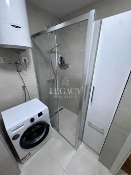 Kupatilo sa tuš kabinom, veš mašinom i belim ormarićem. - image 9