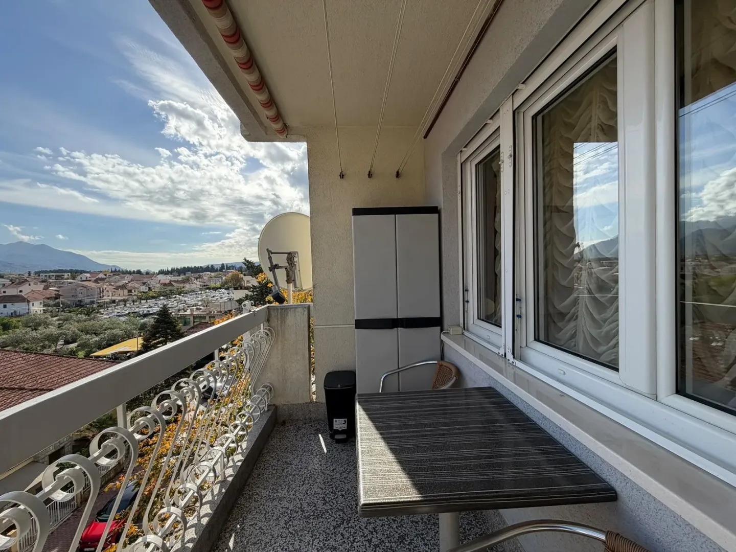 Covered balcony with a table, cabinet, and city view.