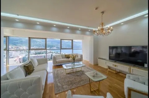 Spacious living room with a sofa set, large TV, and sea views through panoramic windows. - image 4