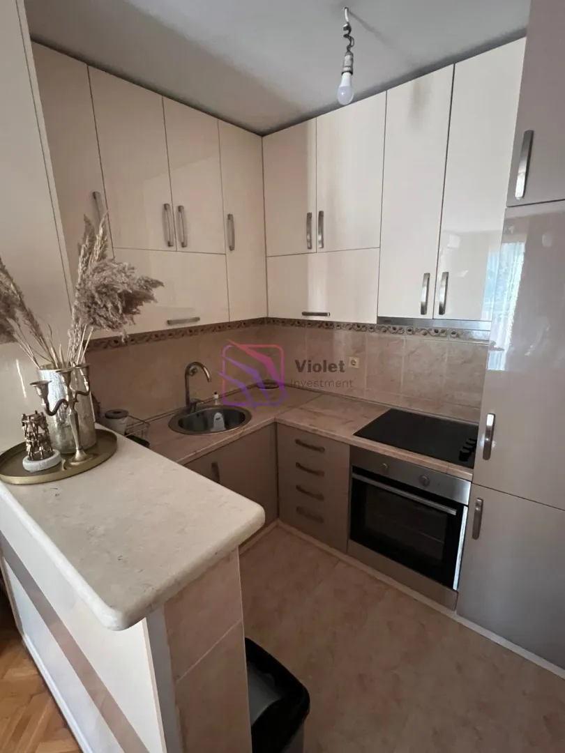 Compact kitchen in light tones equipped with a built-in cooktop, oven, and sink.