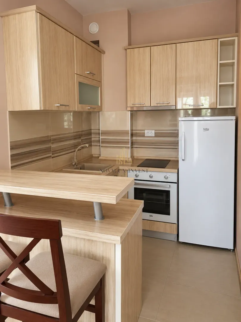 Small kitchen with wooden cabinetry, white refrigerator, and a breakfast bar.