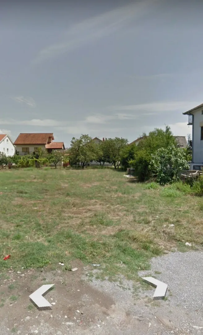 Travnati plac sa kućama u pozadini.