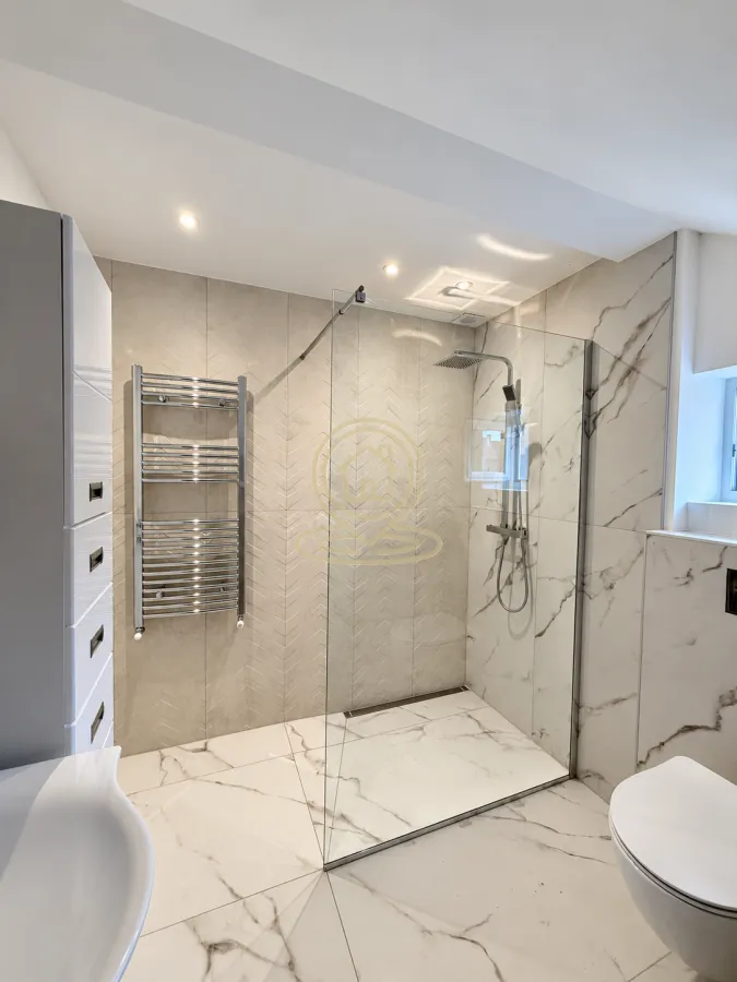 Modernly equipped bathroom with a walk-in shower and white sanitary ware.