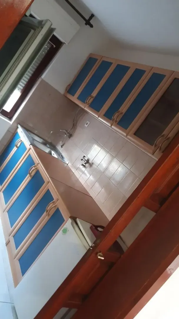 Manja kuhinja sa plavo-bež elementima i sudoperom.
