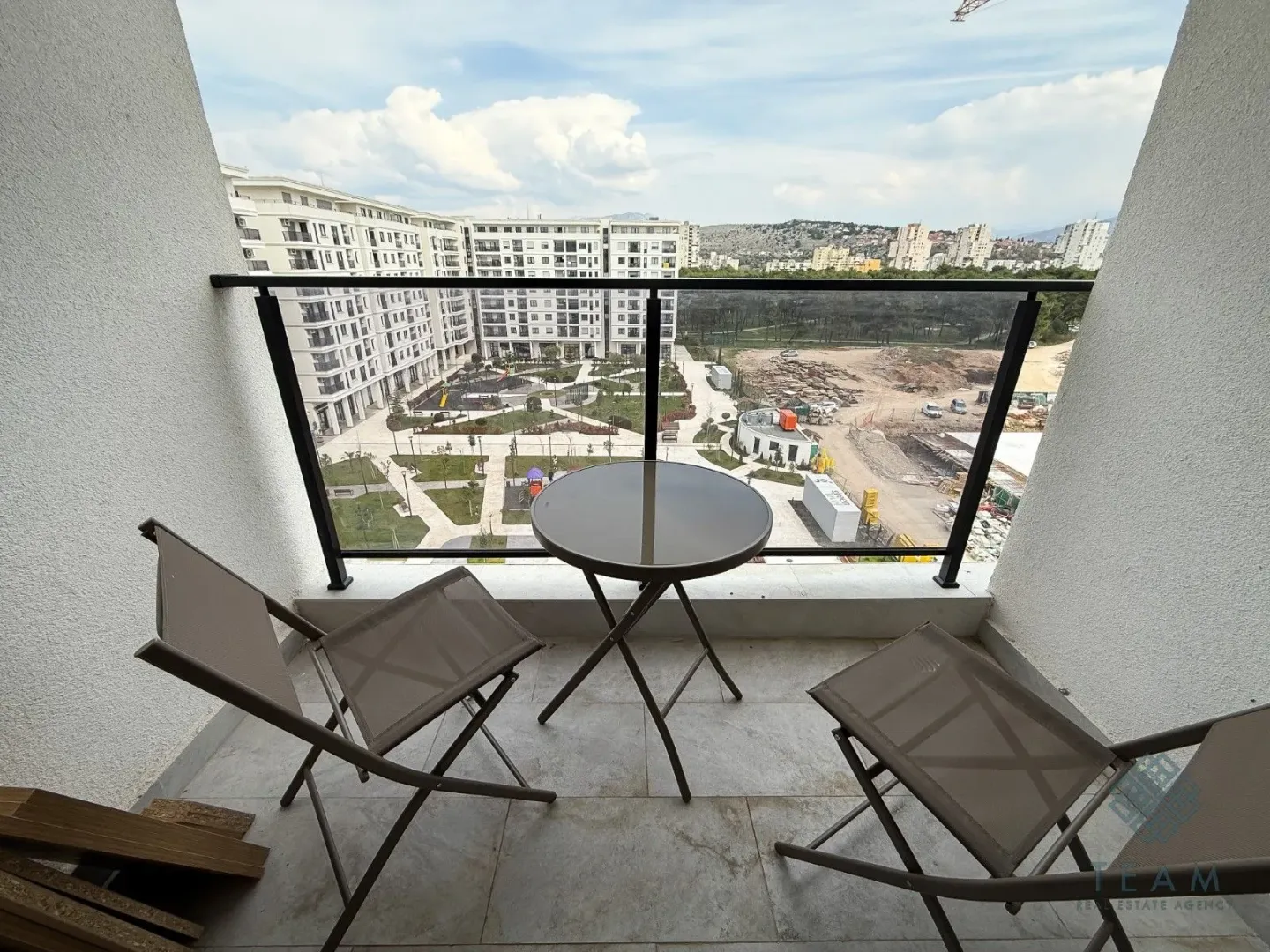 Small balcony with a table and two chairs and a view of the neighborhood.