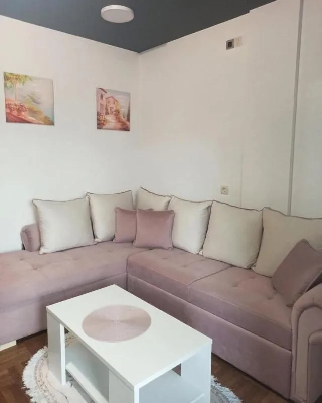 Corner sofa in an antique gold color with a white coffee table and paintings on the wall.