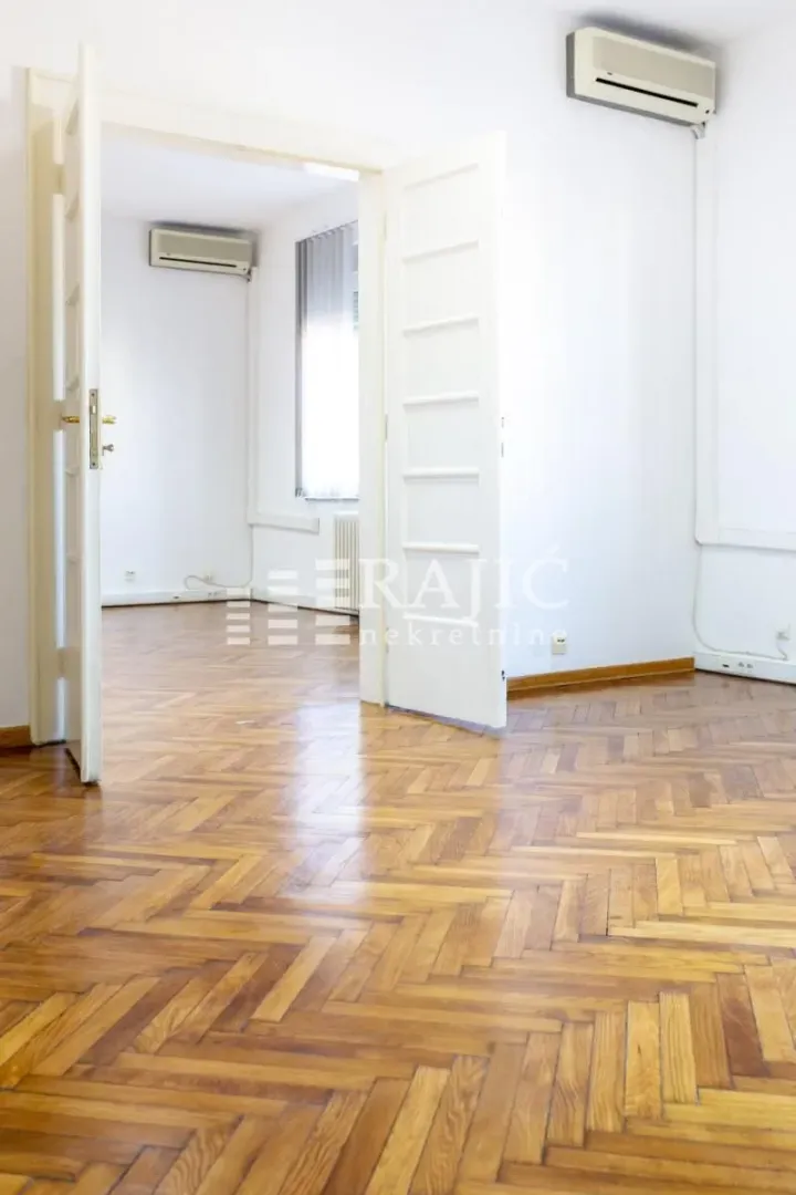 Empty room with parquet flooring and open white doors.