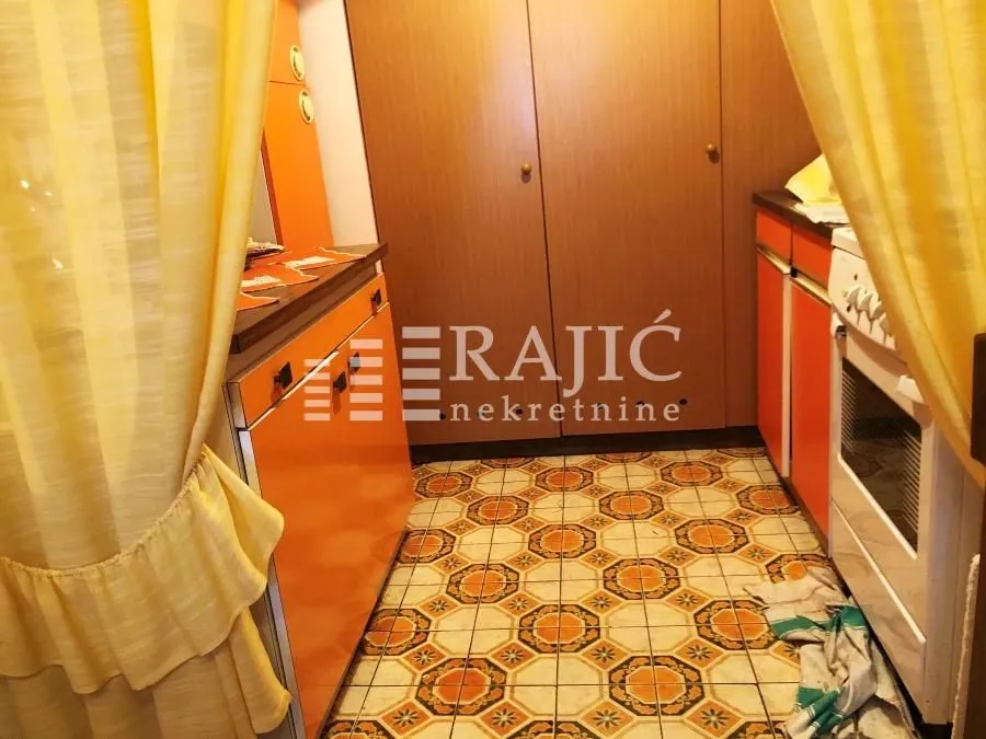 Small kitchen with orange cabinets and tiled flooring.