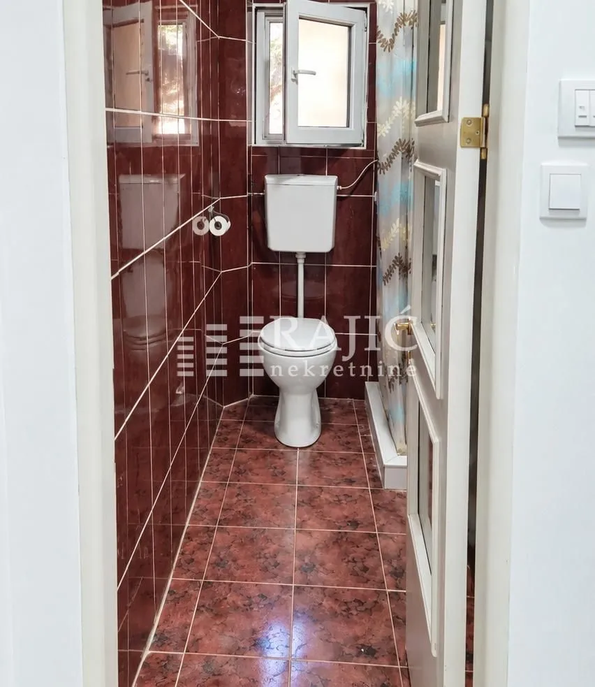 Smaller bathroom with dark red tiles and a toilet.
