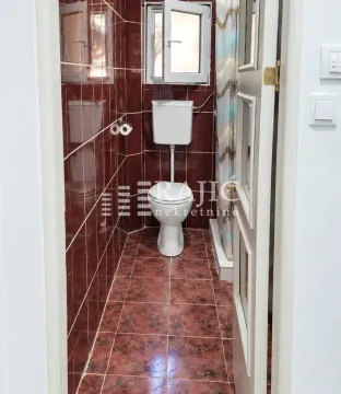 Smaller bathroom with dark red tiles and a toilet. - image 14