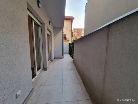 Dugačka popločana terasa sa balkonskim vratima i ogradom. - image 9