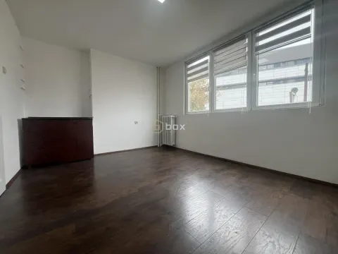 Empty room with dark wooden flooring, white walls, and windows with blinds. - image 6