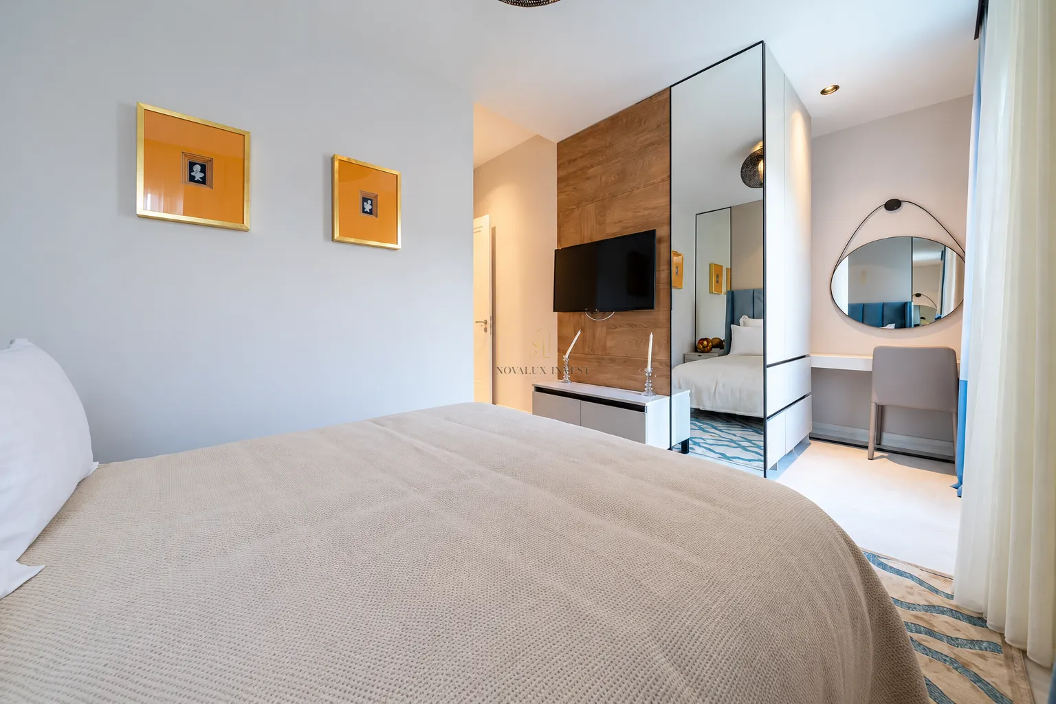 Modern bedroom with a double bed, TV, and built-in mirrored wardrobe.
