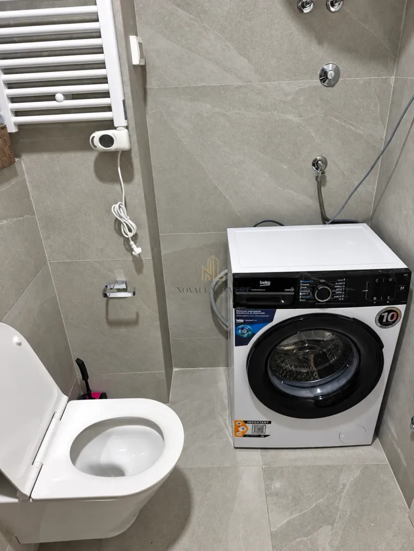 Bathroom equipped with a toilet, radiator, and washing machine.