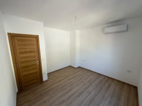 Prazna soba sa bijelim zidovima, drvenim podom i drvenim vratima. - image 15