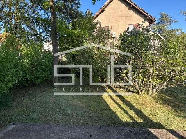 Pogled na dvorište i spoljašnjost kuće okružene zelenilom.