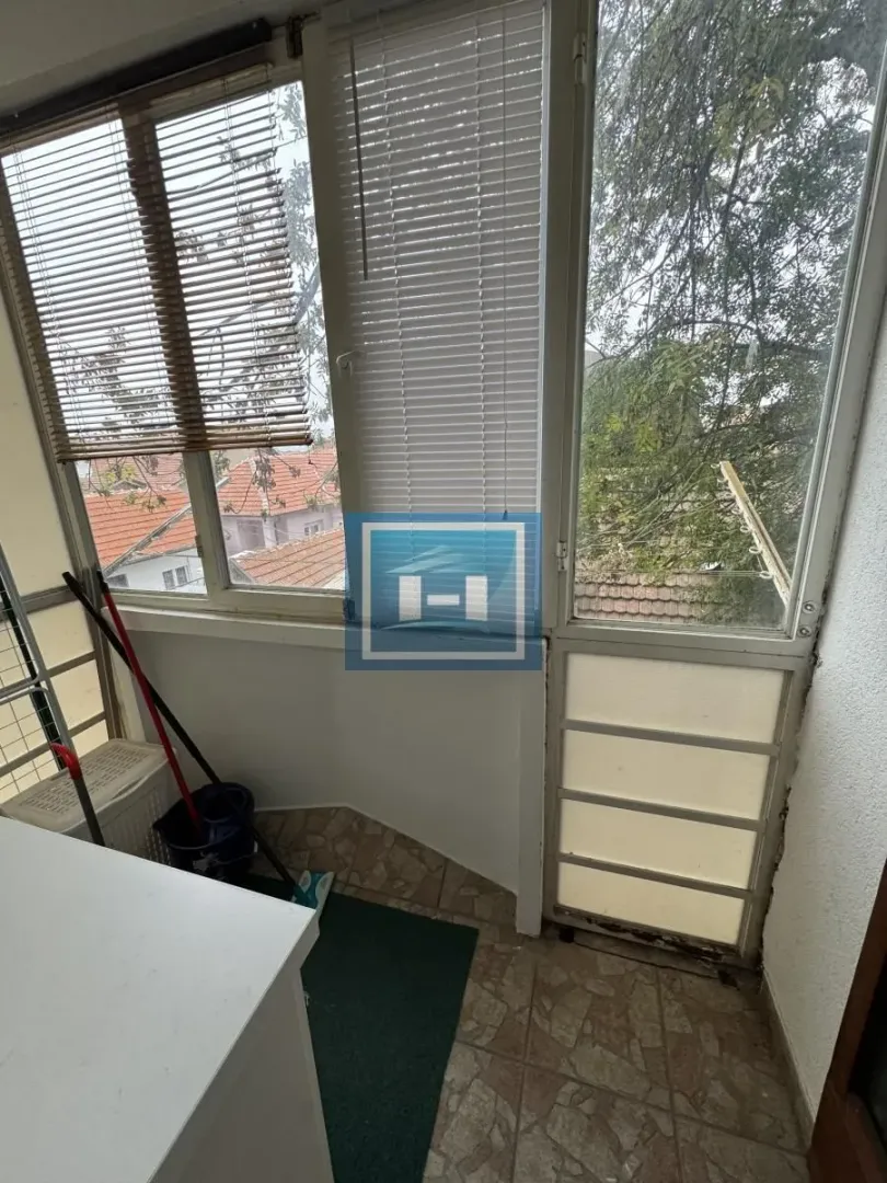 Enclosed balcony with window blinds and a view of the surroundings.