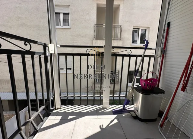 Nenameštena terasa sa priborom za čišćenje i kanti za otpatke.