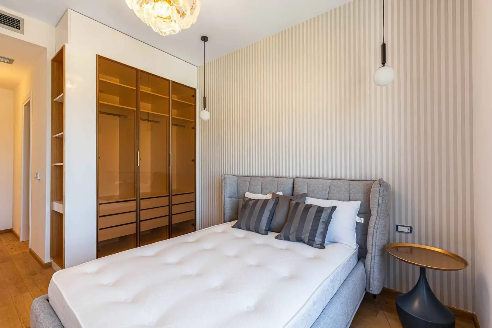 Svijetla spavaća soba sa modernim krevetom i ugradnim garderoberom.