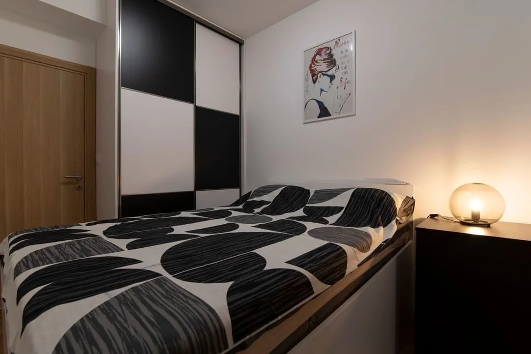 A modern bedroom featuring a built-in wardrobe and a nightstand with a lamp.