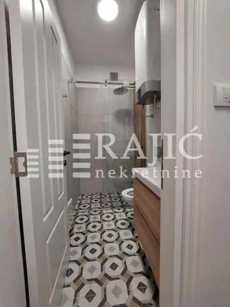View of the bathroom with a walk-in shower through the open door.