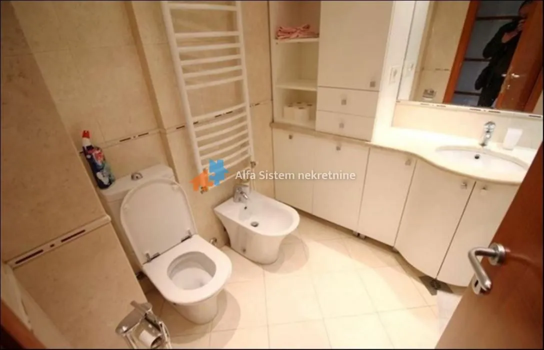Bathroom equipped with a toilet, bidet, washbasin, and built-in storage units.
