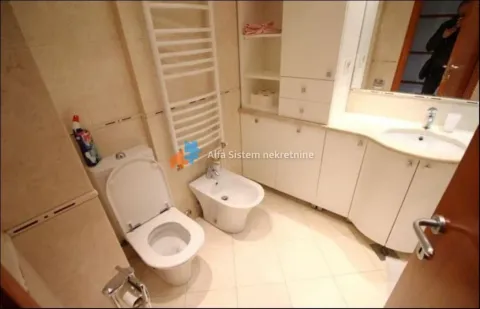 Bathroom equipped with a toilet, bidet, washbasin, and built-in storage units. - image 23