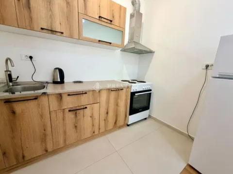 Smaller kitchen with wooden cabinetry, stove, and refrigerator. - image 4