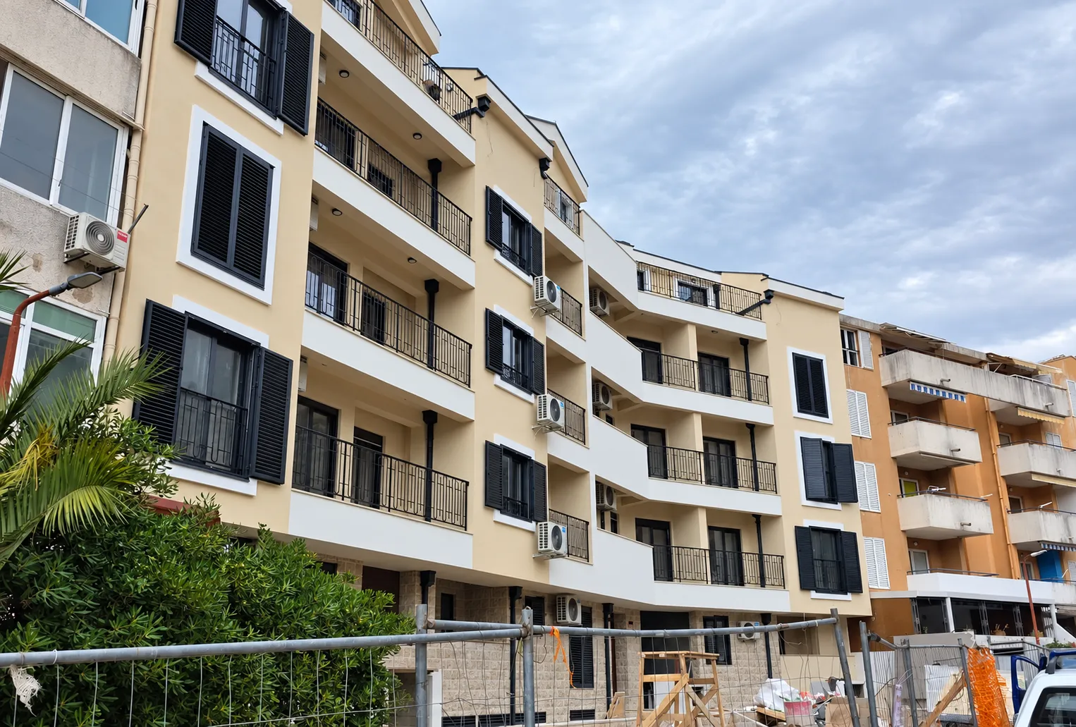 Exterior view of a modern residential building with balconies and dark shutters.