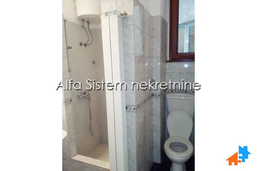 Smaller tiled bathroom with a shower cabin and a toilet.