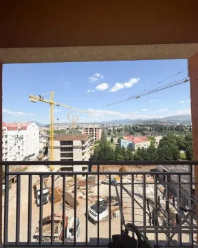 View from the balcony overlooking a construction site and surrounding buildings. - image 3